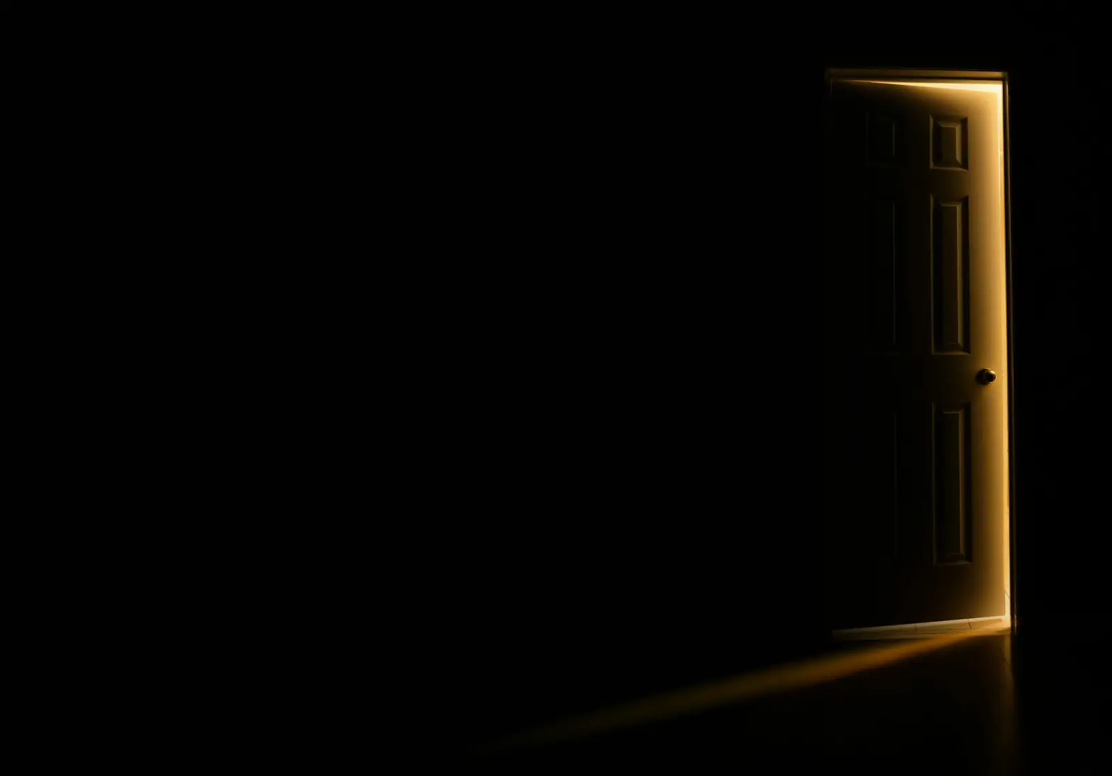 Eine Tür öffnet sich, warmes Licht fällt in einen dunklen Raum