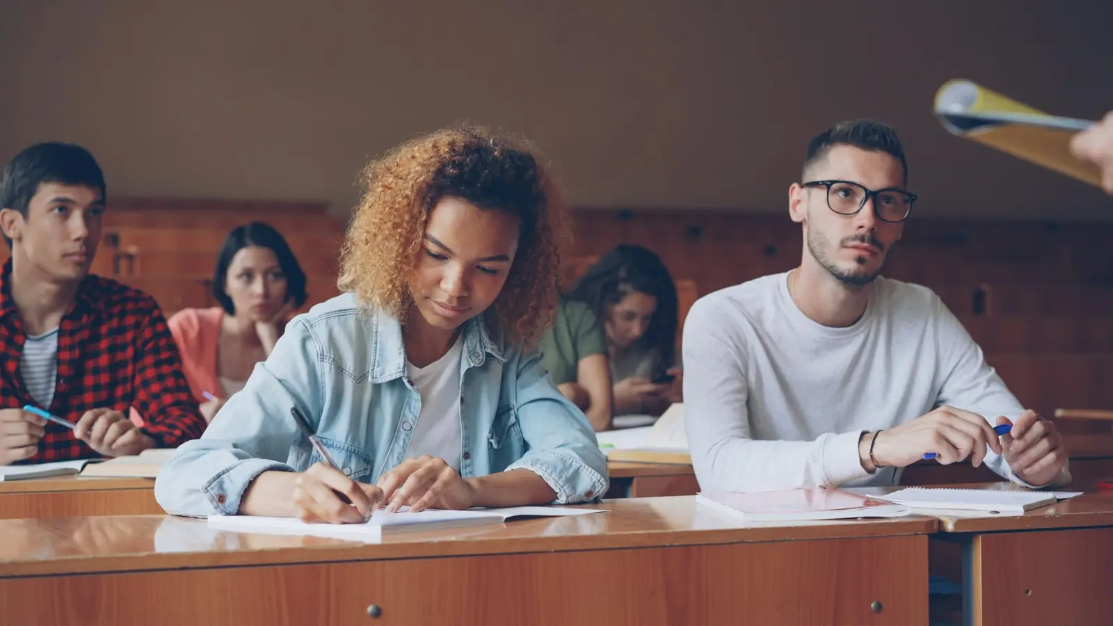 Studierende schreiben konzentriert in einem Hörsaal