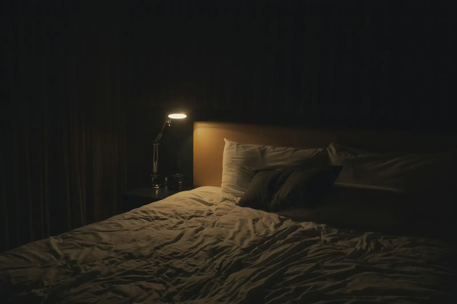 Ein Schlafzimmer bei Nacht, nur die kleine Leselampe neben dem Bett brennt